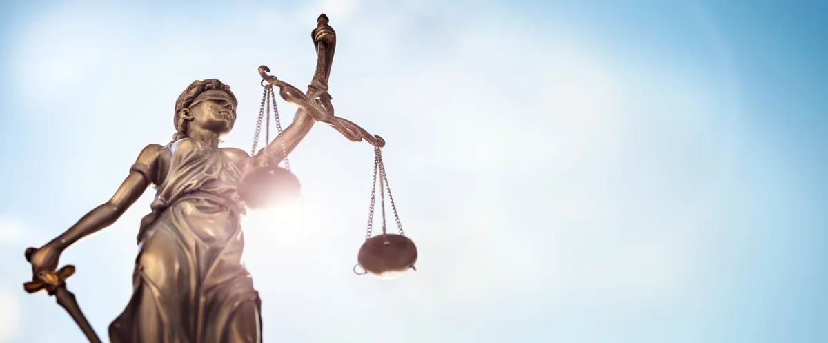 Custodia24 – 24-Stunden-Betreuung – eine Bronzestatue der Justitia, ein gängiges Symbol in der Juristerei, das für Fairness, Objektivität und Recht steht.